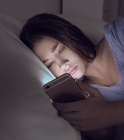 girl using phone in bed