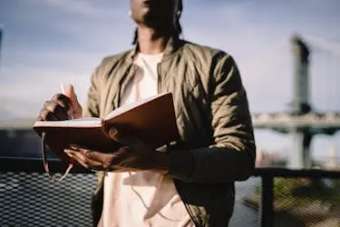 Young man writing on a journal outdoors