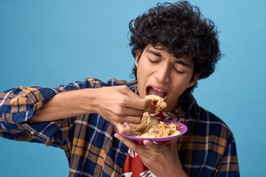 Young man with big appetite eating a delicious asian dish